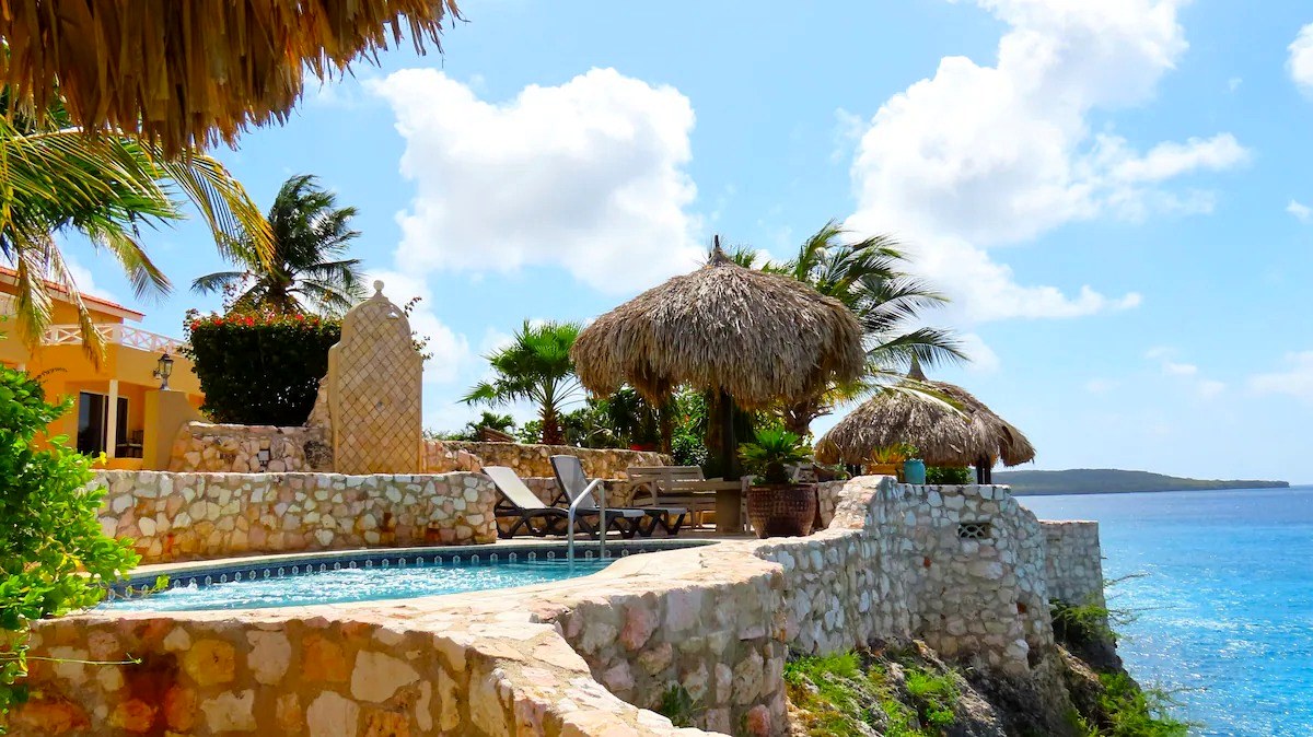 Palapas and sun beds along the cliff-edge pool above the sea