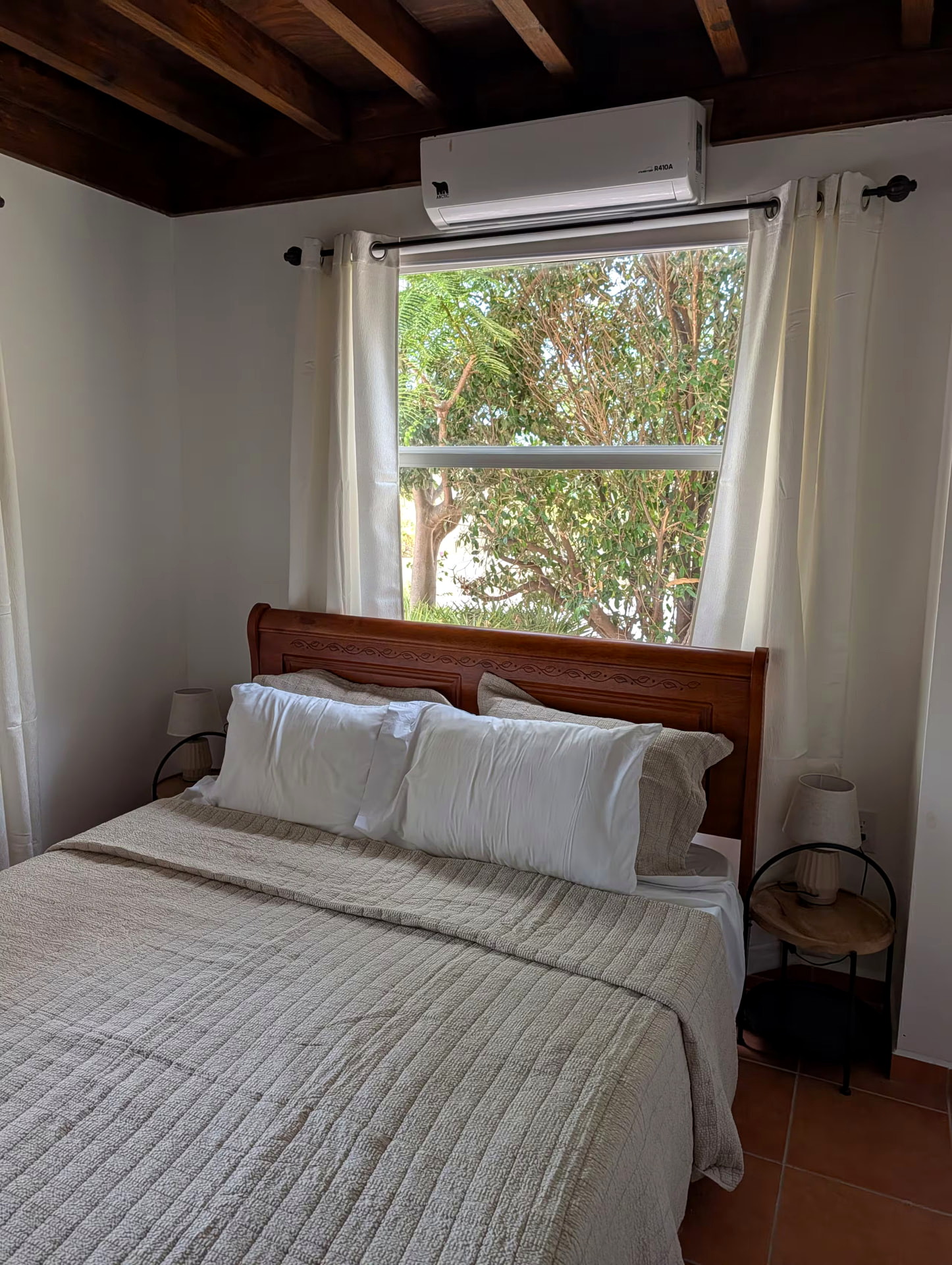 Bedroom with queen bed, wood-beamed ceiling and garden view